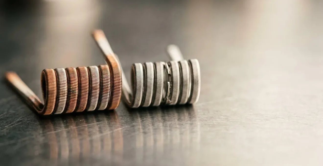 Close-up comparison of handmade vape coil versus factory pre-built coil showing craftsmanship detail