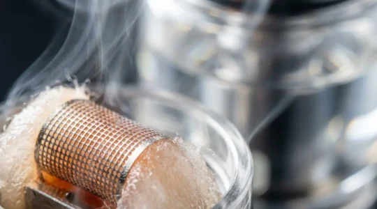 Extreme close-up of mesh coil heating element vaporizing e-liquid with visible vapor formation and precise heat distribution