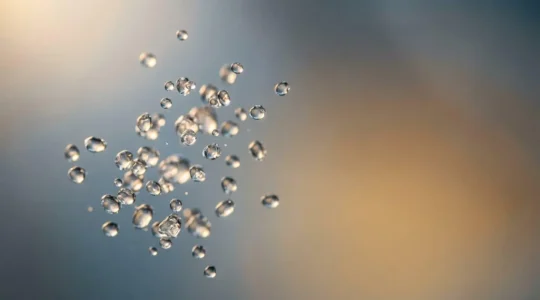 Close-up molecular-inspired composition showing vapor particles and smooth liquid texture representing nicotine salt chemistry