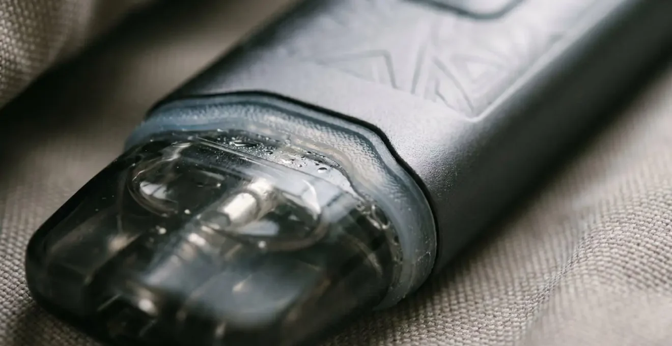 Close-up of vape pod device with visible pressure-induced e-liquid seepage during air travel