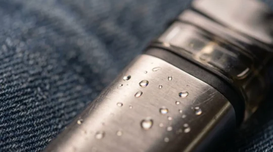 Close-up perspective of a vape device showing condensation and e-liquid residue detail, illustrating common pocket leakage issues